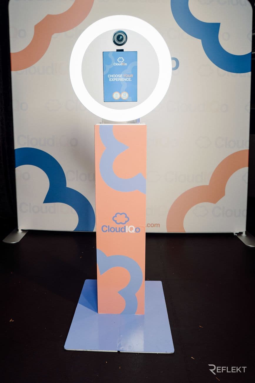 Photo booth kiosk wrapped in a client's branding in front of a matching backdrop