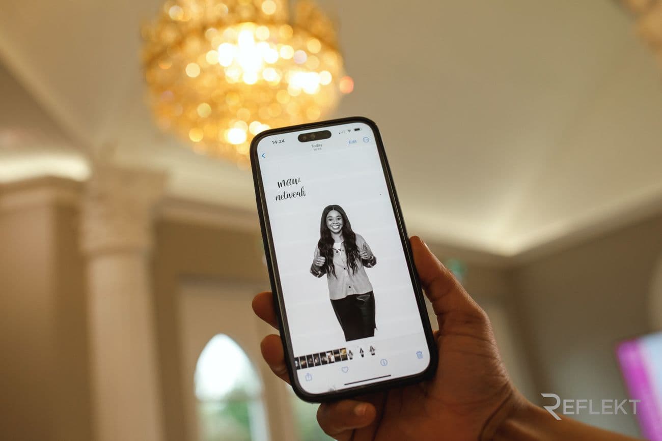 Phone showing a black-and-white glam booth portrait in a ballroom