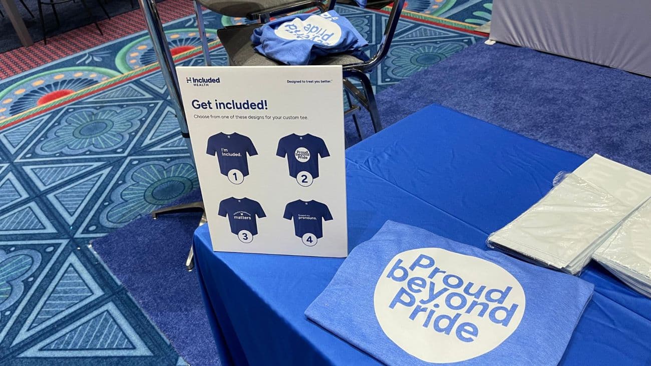 Live heat press station with a design menu and custom printed totes at a conference