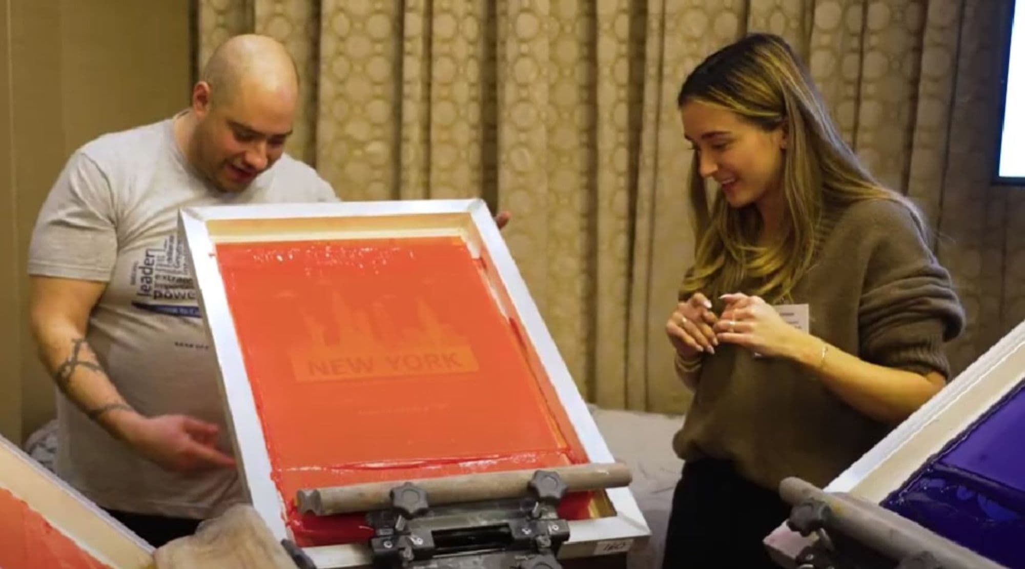 Printer pulling a live screen print for a smiling guest at a corporate event