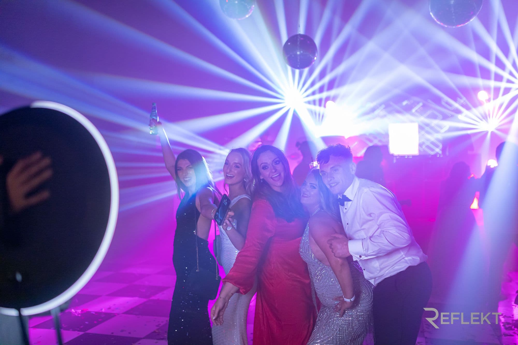 Guests on a dance floor posing for a Reflekt roaming photo booth
