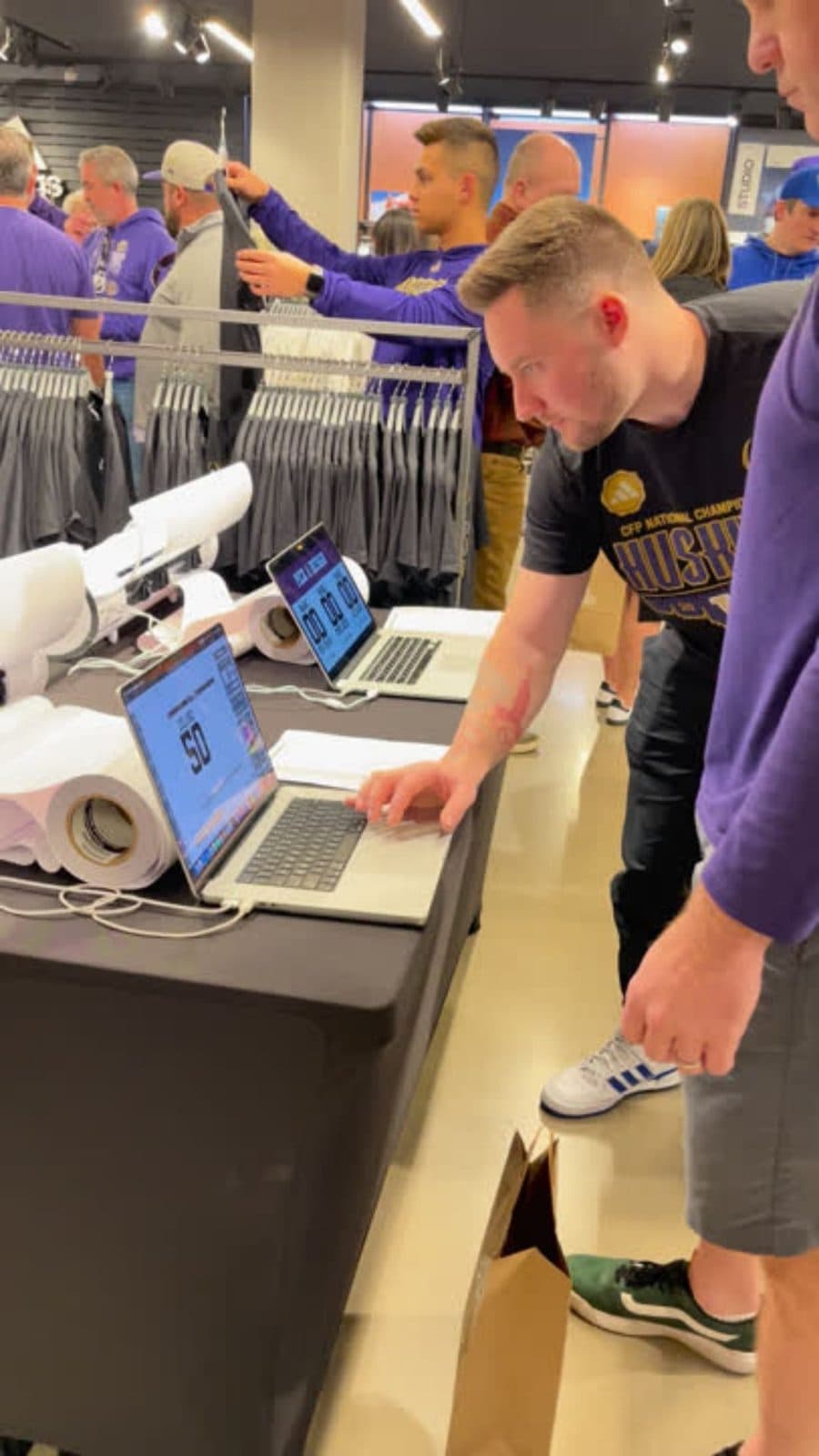 Staff personalizing a shirt at a live printing station inside a team store