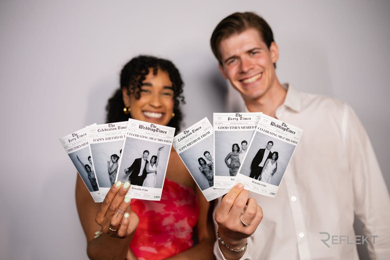 Guests holding custom newspaper-style photo booth prints