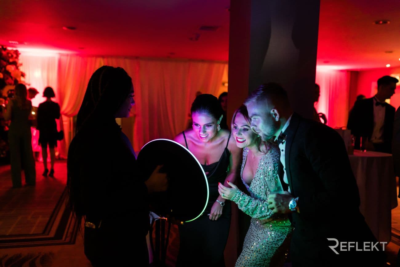 Guests posing for a roaming photo booth under red event lighting