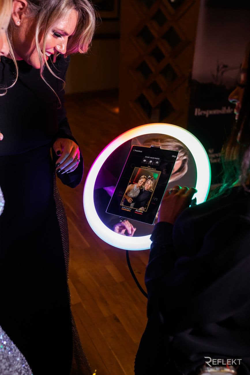 Guest tapping the screen of a ring-light photo booth at an evening event